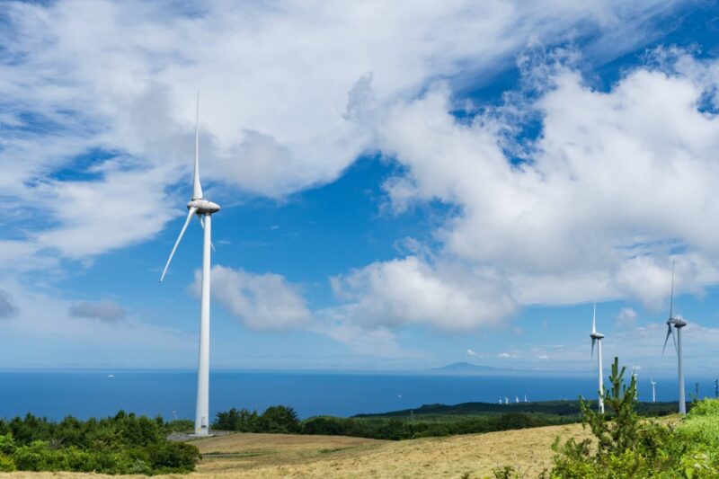 にかほ第二風力発電所の風車と遠くに見える男鹿半島