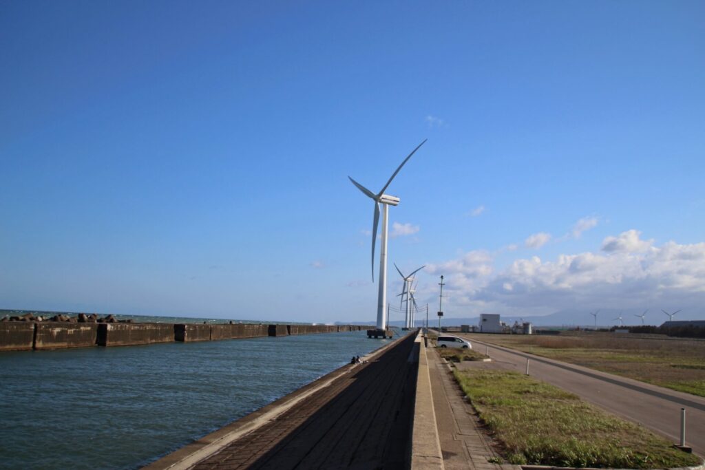 水路上に立つ、JRE酒田風力発電所の風車群